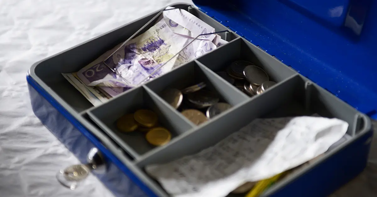 En öppen kassalåda med svenska sedlar och mynt i olika valörer samt en kvittorulle inne i lådan