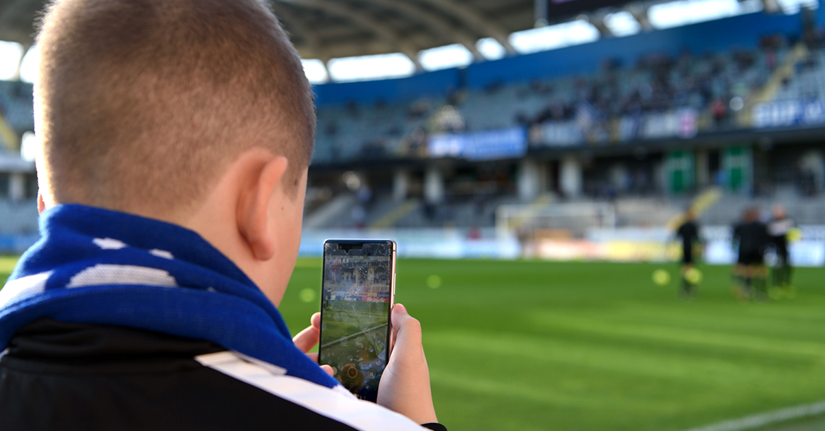 man filmar fotbollsmatch med mobiltelefon